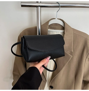 Détail du sac à bandoulière en cuir noir texturé avec grain litchi et design minimaliste