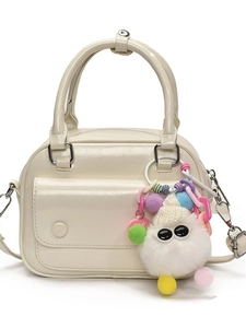 Cream patent leather pillow bag with top handle and fluffy monster keychain accessory