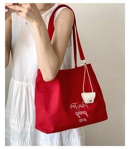 Detail of red canvas tote bag with Paris going on embroidery and white hanging charm