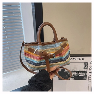 Close-up of colorful woven straw tote with brown leather handles and metal buckle detail