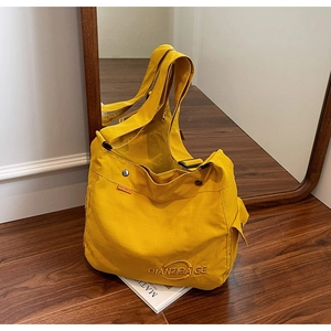 Dettaglio della borsa tote in tela gialla con tasca laterale e tracolla regolabile