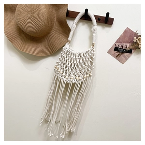 Detail of handmade macramé bag with natural wooden beads and long fringe tassel