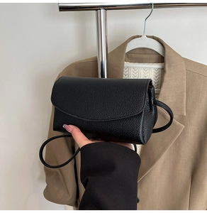 Détail d'un petit sac carré noir en cuir à texture litchi avec fermeture à rabat