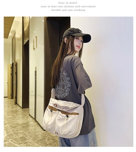 Detail of a beige nylon messenger bag with drawstring pockets and brown stitching accents