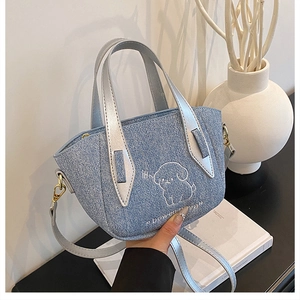 Detailed embroidery of a white puppy on a blue denim tote with silver metallic straps