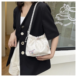 Close-up of white floral embossed canvas bag with embroidery and silver chain strap