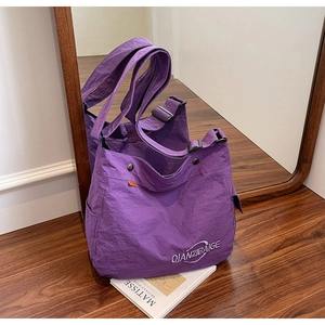 Dettaglio della borsa tote in tela viola con tracolla regolabile e tasca laterale