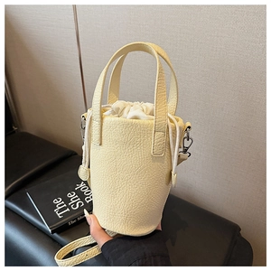 Detailed top view of a light yellow bucket bag with lychee texture and drawstring pouch