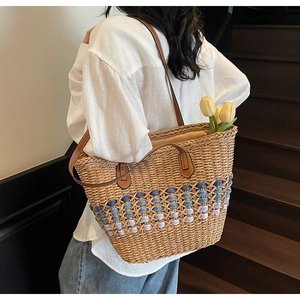Détail d'un sac cabas en paille tressée avec dégradé bleu et anses en cuir élégantes