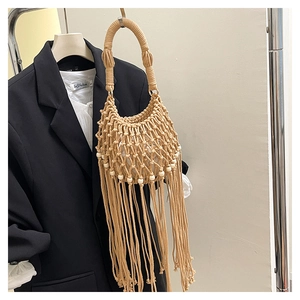 Detail of bohemian woven handbag with mesh knit, hanging tassels, and white beads