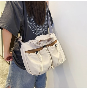 Detail of cream pleated crossbody bag with dual drawstring pockets and wide strap