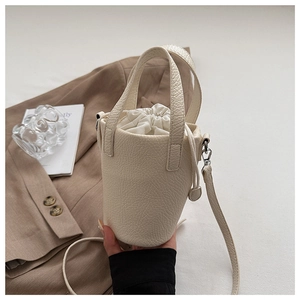 Detail of cream bucket bag showing lychee grain leather texture and drawstring closure