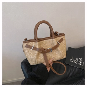 Detailed close-up of woven straw tote bag with brown leather trim and metal clasp