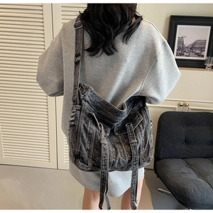 Detail of vintage washed denim crossbody bag featuring distressed edges and metal buckles