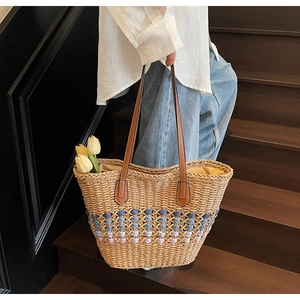 Détail d'un sac cabas en paille tressée avec motifs géométriques et anses en cuir