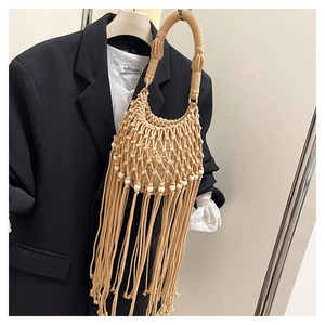 Detail of bohemian beige woven tote bag with fringe tassels and white wooden beads