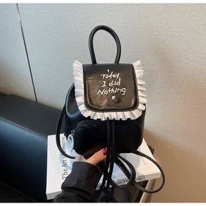 Detail of a black mini backpack with white ruffle trim and letter embroidery