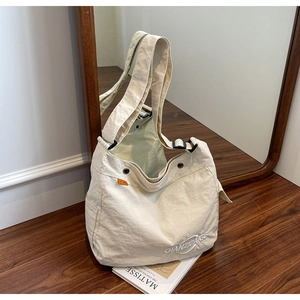Dettaglio della borsa tote in tela crema con trama stropicciata e tracolla nera