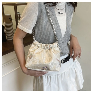 Close-up of floral jacquard shoulder bag featuring silver chain strap and drawstring closure