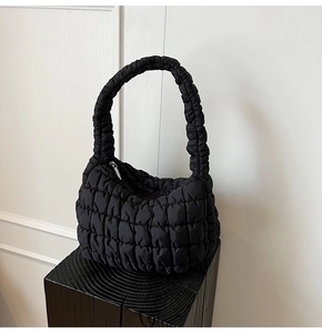 Detailed view of black quilted bubble bag featuring glossy texture and silver zipper