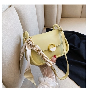 Détail d'un sac selle avec boucle en émail blanc et ruban de soie décoratif sur la chaîne