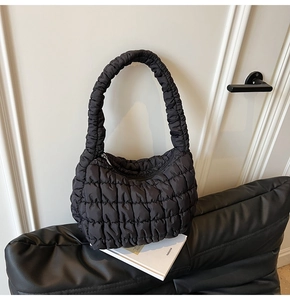 Detail shot of black quilted shoulder bag featuring soft pleated nylon fabric and texture