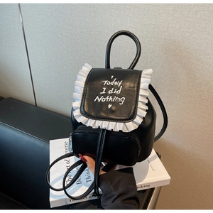 Detail of a black leather mini backpack with white ruffle trim and embroidered lettering
