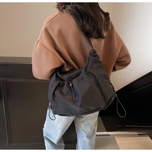Detailed back view of a large black nylon crossbody bag with adjustable strap on model