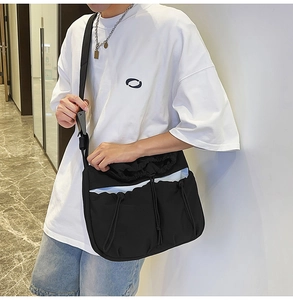Detail of black nylon pleated crossbody bag with drawstring pockets and adjustable strap
