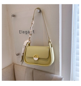 Détail du sac selle vert clair avec boucle dorée et blanche et foulard décoratif en soie
