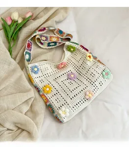 Details einer weißen Häkeltasche mit bunten 3D-Blumen und geometrischem Webgurt