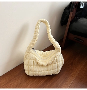Detail of beige quilted bubble handbag with soft puff texture and zipper closure