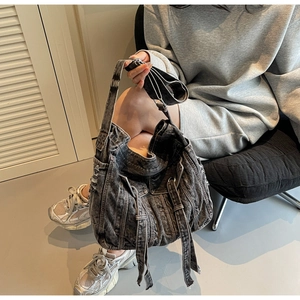 Detail of retro washed denim hobo bag featuring street style frayed edges and metal buckles