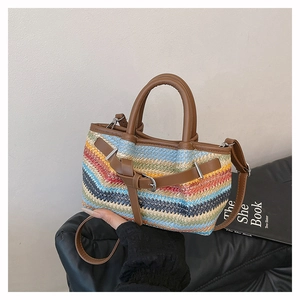 Detail of colorful woven wave pattern on a straw tote bag with brown leather straps