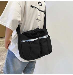Adjustable wide strap on black nylon messenger bag with drawstring cargo pocket detail