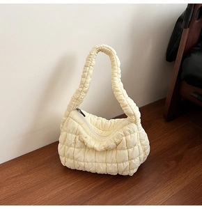 Close-up of cream quilted puffer bag showing soft pleated texture and shoulder strap