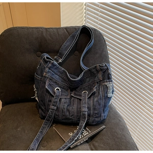 Detail of vintage denim tote bag with functional pockets and distressed frayed edges