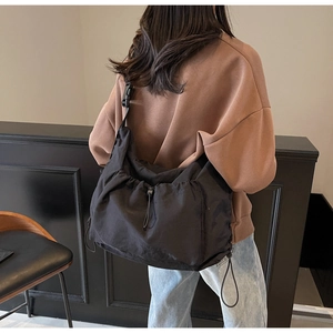 Detailed view of black nylon dumpling bag with adjustable drawstring on female model