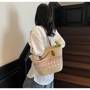Détail du sac cabas en paille tissé avec motifs de vagues roses et anses en cuir marron