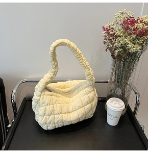 Detail of light yellow quilted puffy cloud bag with textured nylon and zipper closure