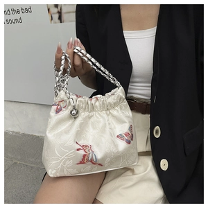 Detail of floral embroidery and butterfly pattern on off-white jacquard handbag