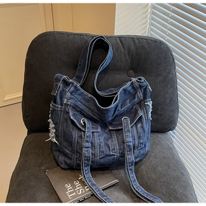 Detailed close-up of retro denim tote bag featuring distressed edges and metal ring decor