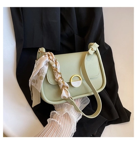 Détail du sac selle vert menthe avec boucle dorée, bandoulière chaîne et foulard à pois