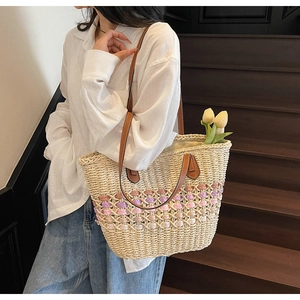 Détail du sac cabas en paille tissée multicolore avec anses en cuir et rivets