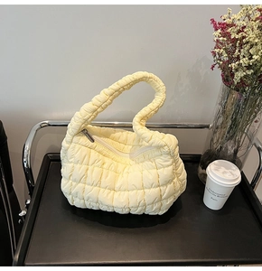 Detail of light yellow quilted bubble handbag with puff texture and top zipper