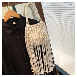 Detail of bohemian hand-woven cotton bucket bag with wooden beads and long fringe tassels