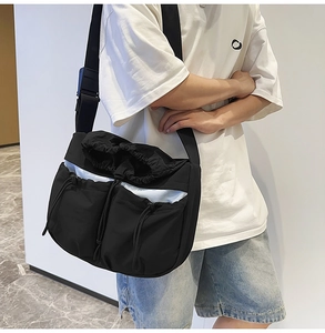 Detail of black utility messenger bag with drawstring pockets and adjustable shoulder strap