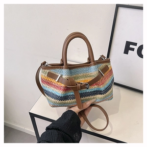 Detailed shot of multi-colored woven straw tote with brown faux leather handle and strap