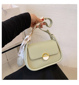 Détail du sac selle vert clair avec foulard élégant en soie autour de l'anse