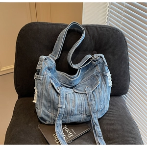 Detailed macro view of retro denim shoulder bag featuring functional pockets and floral trim